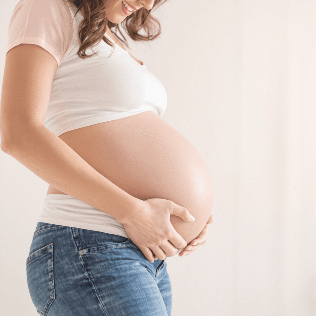 Kobieta w ciąży delikatnie trzymająca brzuch, otoczona pastelowymi kolorami i subtelnymi ikonami medycznymi takimi jak waga i wykres BMI.